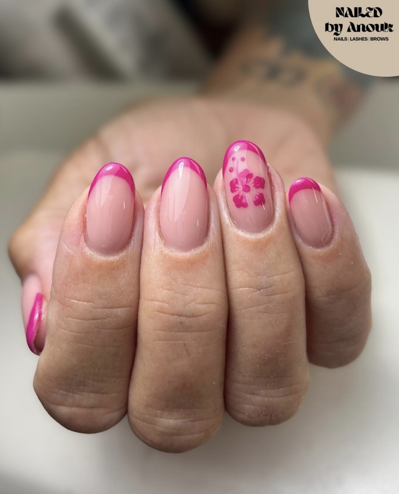 Nagels met fel roze French tips en een roze bloem op één nagel