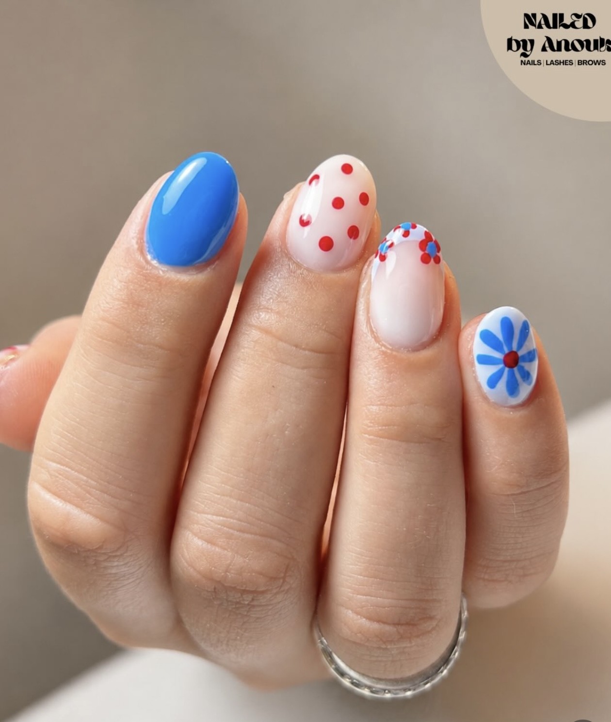Nagels in kobaltblauw, met rode stippen en kleine blauwe bloemen
