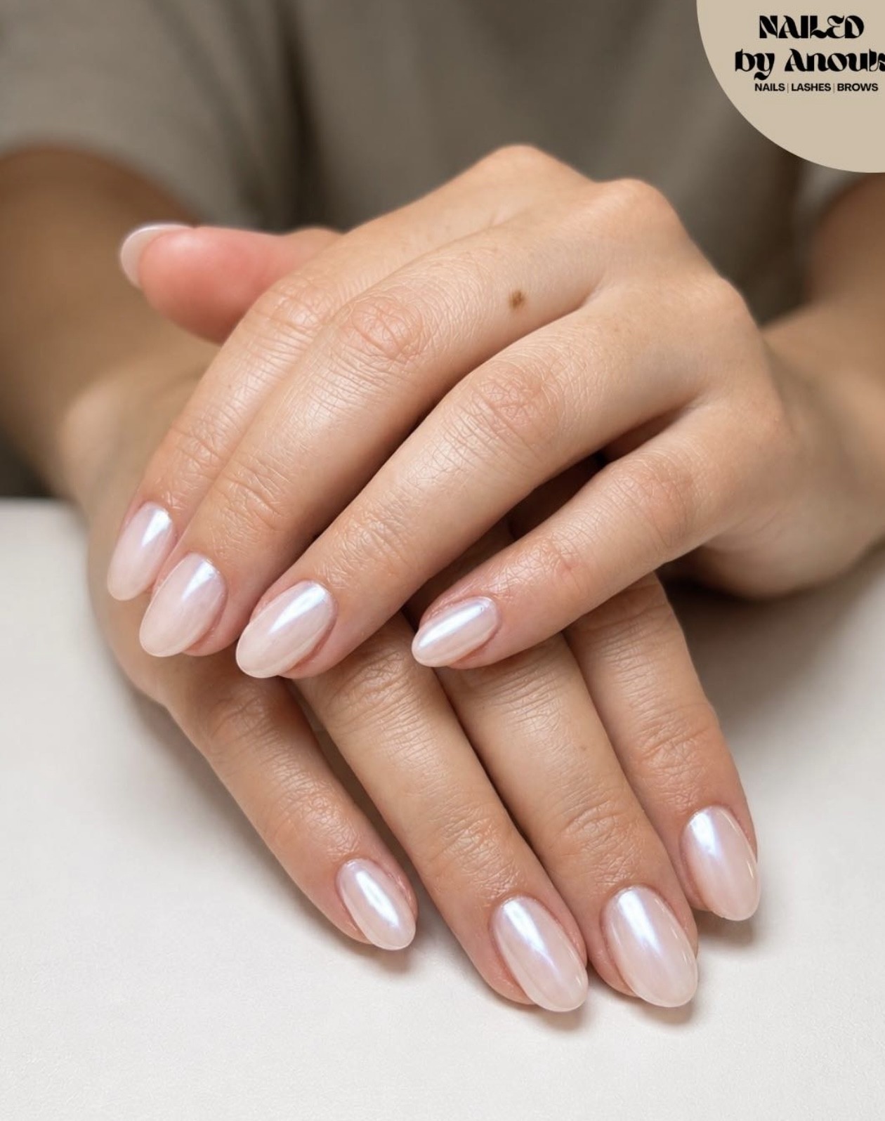 Handen over elkaar met parelmoer melkwitte nagels